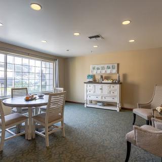 A cozy dining area with a round table, chairs, and a large window allowing natural light in.
