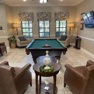 A cozy game room featuring a pool table, comfortable seating, and a television.