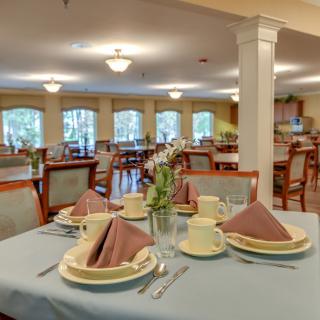 An elegantly set dining room table with plates, cups, and folded napkins in a well-lit restaurant.