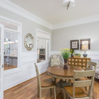 A cozy dining room with a round wooden table and chairs, featuring stylish decor and soft neutral tones.