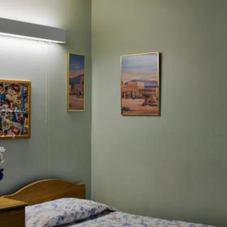 A cozy bedroom with paintings on the wall and a bed with patterned sheets.