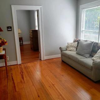 A cozy living room with hardwood floors and a sofa by the window.