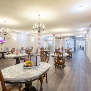 A beautifully decorated restaurant interior with multiple tables and chairs, featuring elegant chandeliers.