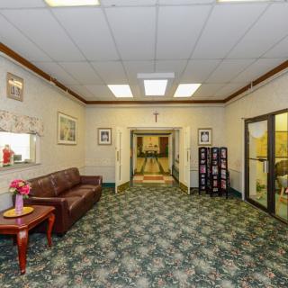 A well-lit lobby area featuring a sofa, table with flowers, and decorative elements.