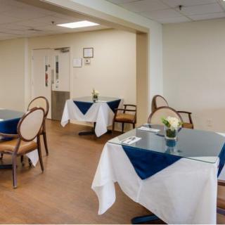 A neatly arranged dining area with tables and chairs, featuring blue and white tablecloths and floral decorations.