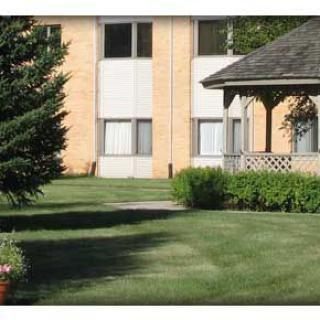 A tranquil residential area with an apartment building, a gazebo, and well-maintained green lawn.
