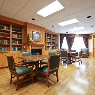 A cozy library room with wooden shelves, a table, and chairs.