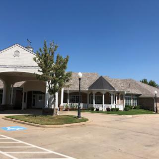 A well-designed commercial building with a spacious parking lot and landscaping under a clear blue sky.