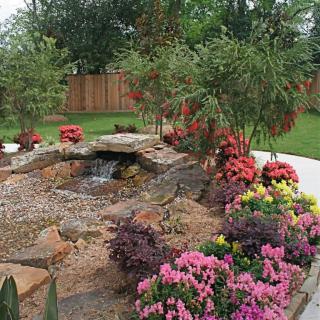 A beautifully landscaped garden with vibrant flowers and a rock feature.