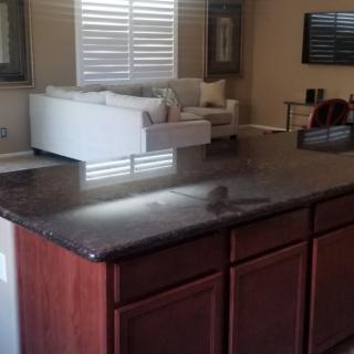 A kitchen countertop with a view of the living room featuring a white sofa.