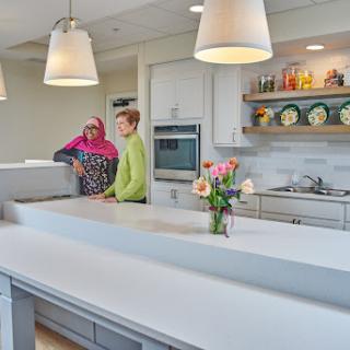 A bright and modern kitchen featuring two people engaged in conversation while surrounded by floral arrangements and stylish decor.