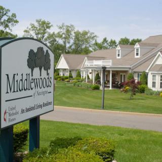 A view of Middlewoods assisted living community with a sign in the foreground and residential buildings in the background.