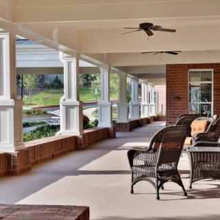 A spacious covered porch with wicker furniture and a ceiling fan, offering a relaxing outdoor seating area.