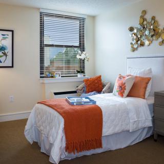 Modern bedroom with orange accents and stylish decor.