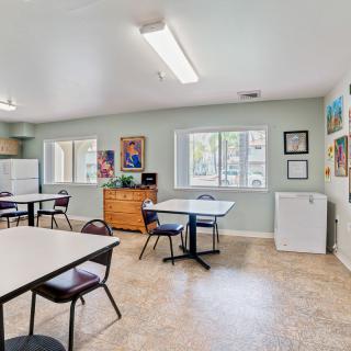 A communal room with tables, chairs, and artwork on the walls.