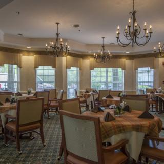 A warmly lit dining room with elegantly arranged tables and chandeliers.