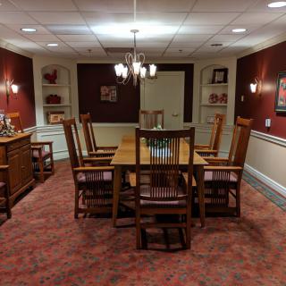 A warmly decorated dining room featuring a wooden table and chairs, with elegant lighting and artwork on the walls.