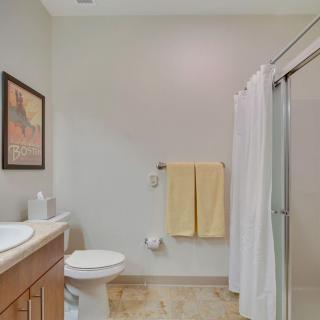 A clean bathroom with a shower, sink, and neatly hung towels.