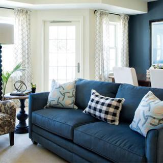 A modern living room with a blue sofa, decorative pillows, and ample natural light.