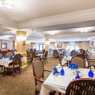 A spacious and well-decorated dining room with neatly arranged tables, each set with blue glassware.