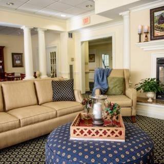 A cozy living room with a comfortable sofa, a patterned ottoman, and elegant home decor.