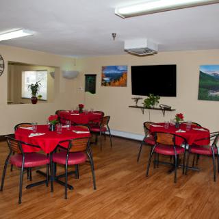 A cozy dining area featuring red-covered tables and wooden flooring, perfect for gatherings.