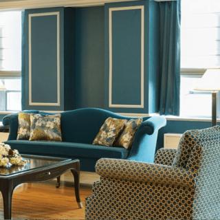A cozy living room with elegant furnishings, featuring a teal sofa and patterned armchair.