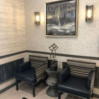 A cozy lobby seating area with two chairs, a small table, and wall art.
