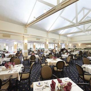 A spacious and well-lit restaurant dining room with neatly arranged tables and chairs.