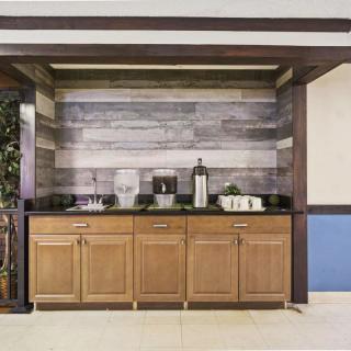 A cozy beverage area featuring wooden cabinets and a coffee station with a rustic wood-paneled backdrop.