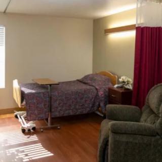 A hospital room with a bed, recliner, and privacy curtain.