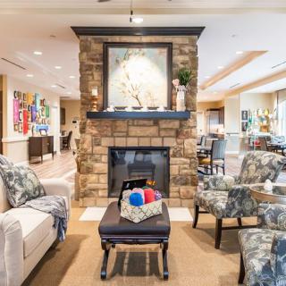 A cozy and modern living room featuring a stone fireplace, comfortable seating, and vibrant artwork.