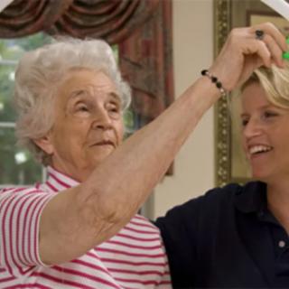 An elderly woman playfully interacts with a younger woman inside a home.