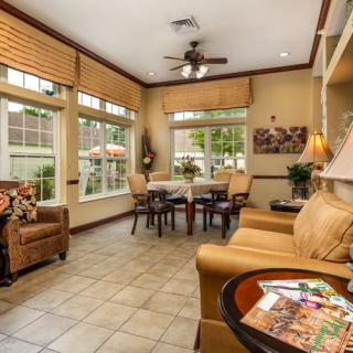 A cozy living room with ample natural light, featuring comfortable seating and large windows.