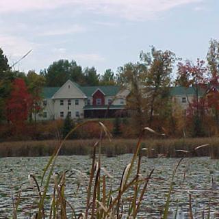 A tranquil scene featuring a serene pond with a building in the background, surrounded by colorful autumn trees.