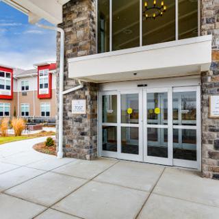A modern building entrance featuring sliding glass doors and a stone exterior.