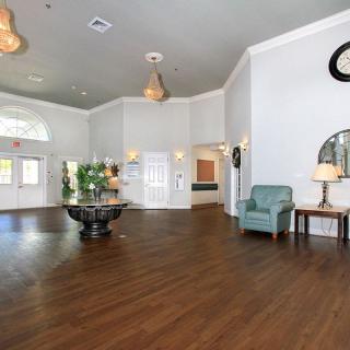 A spacious lobby with hardwood flooring, decorated with plants and stylish furniture.