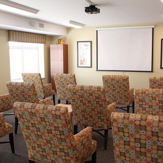 A small conference room with patterned chairs facing a projector screen.