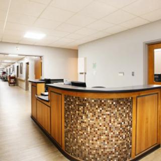 This image shows a hospital corridor with a reception desk and office doors.