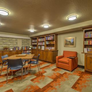 Cozy library room with bookshelves, a table, chairs, and an armchair.