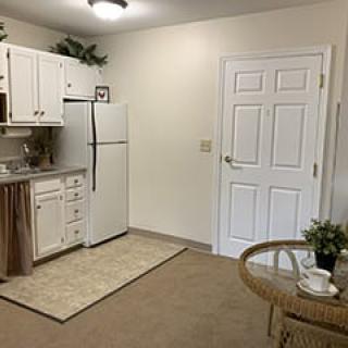 Minimalist kitchen area in an apartment with white cabinets and a small dining table.