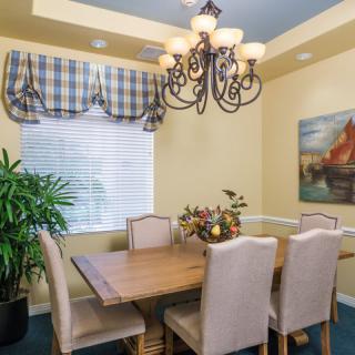 A cozy dining room with a wooden table, six chairs, and a decorative chandelier.
