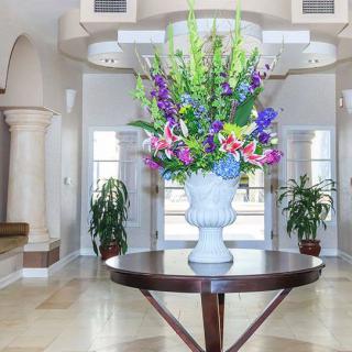 A large floral arrangement in a vase sits on a wooden table in an elegantly designed lobby.