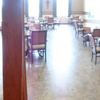An empty dining room with neatly arranged chairs and tables in front of large windows.