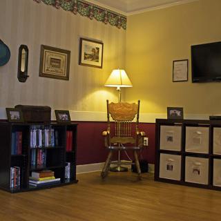 A cozy living room interior featuring a lamp, bookshelves, and a television.