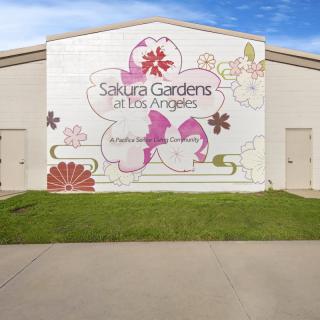 A mural on a building displaying floral designs and the text 'Sakura Gardens Los Angeles'.