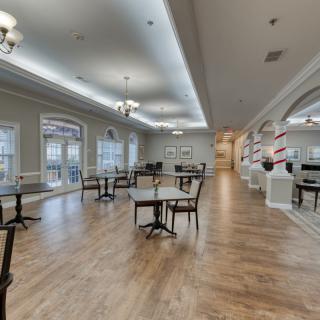 An elegant dining area with hardwood floors, tables, and chandeliers.