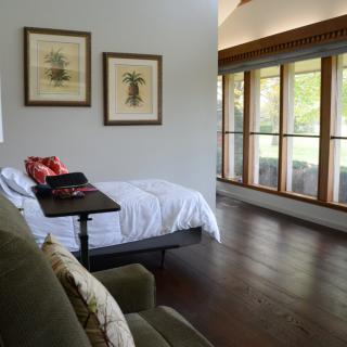 A modern minimalist bedroom with large windows and wood flooring.
