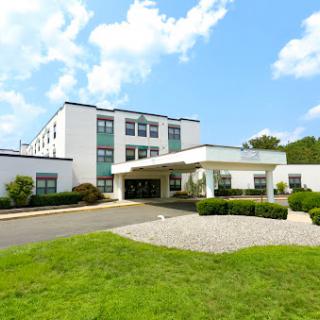 A modern hotel building set against a clear blue sky, surrounded by well-maintained landscaping.