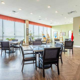 A modern dining area with wooden flooring and large windows.